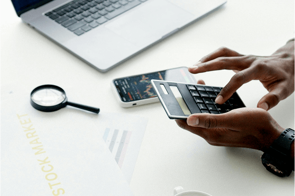  ภาพแสดงบุคคลกำลังฝึกคำนวณและวางแผนการเทรด - Ultima Markets